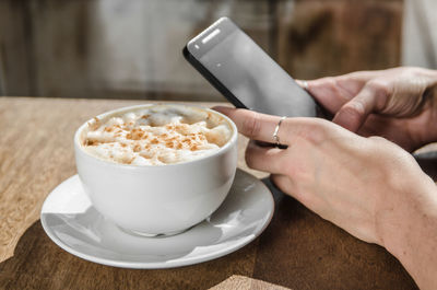Close-up of hands holding coffee cup on table