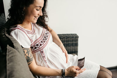 Close-up of smiling pregnant woman looking at x ray in home