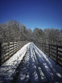 Snow covered footbridge against clear blue sky