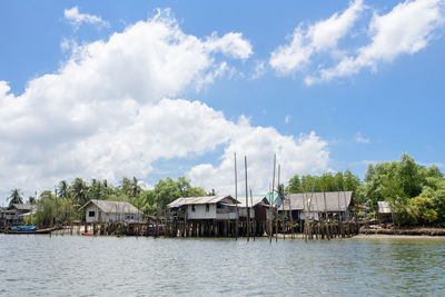 Houses by river and buildings against sky