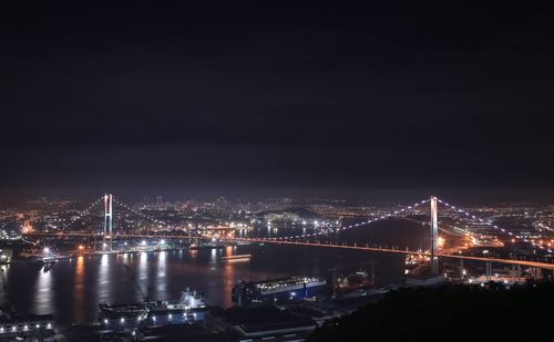 Illuminated bridge over river in city at night