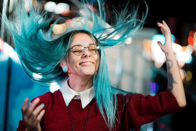 Happy woman with tousled hair gesturing at night