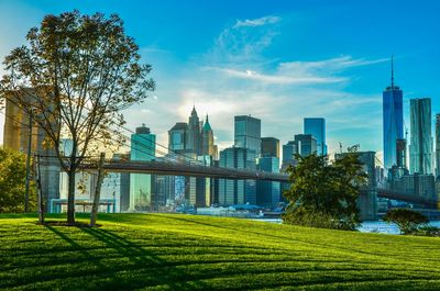 Park by brooklyn bridge and cityscape against sky