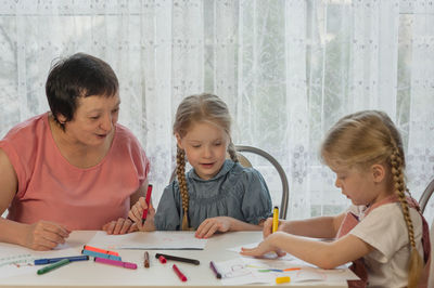 Grandmother sitting with granddaughters during painting