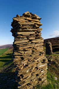 Stack of rocks on field against sky