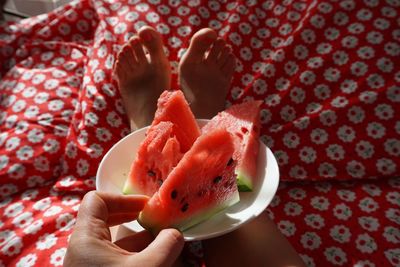 Low section of woman with watermelon slices on bed