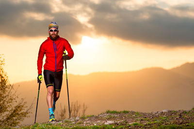 Man standing on mountain against sky during sunset