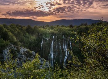 Scenic view of waterfall against sky during sunset