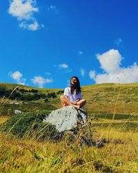 Full length of woman sitting on field against sky