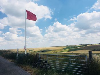 Flag on hill against cloudy sky