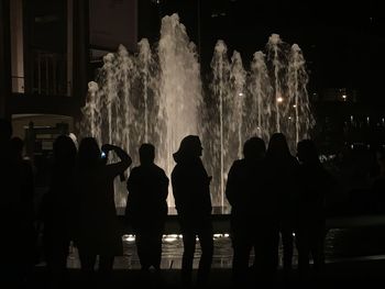 Silhouette of people in fountain at night