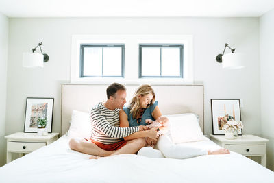 Straight on portrait of a mother and father holding their newborn girl