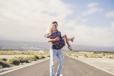 Man carrying woman while standing on road