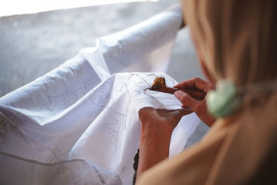 Midsection of woman making batik painting