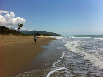 Woman standing at beach against sky