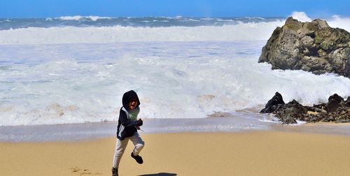 Boy standing on beach against sky