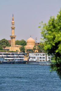 Buildings by sea against clear sky