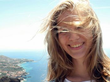 Portrait of young woman at beach against sky