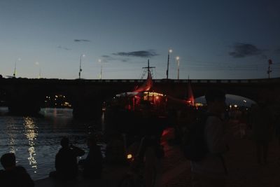 Silhouette people in illuminated city against sky at night