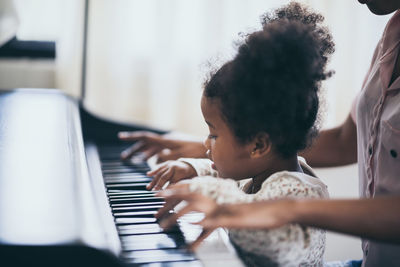 Midsection of woman playing piano with daughter