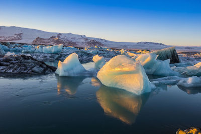 Icebergs at beach against sky during winter