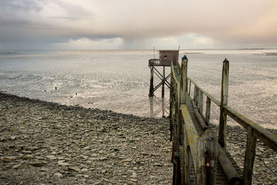 Scenic view of sea and fishing hut against sky