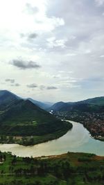 Scenic view of river by mountains against sky