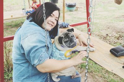 Portrait of woman with dog sitting on swing 