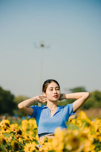 Portrait of young woman standing against sky