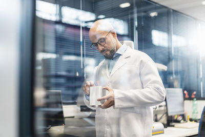Technician wearing lab coat examining workpiece