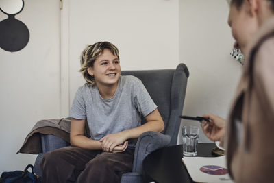 Smiling female student listening to counselor discussing in school office