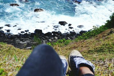 Low section of man standing on rock by sea