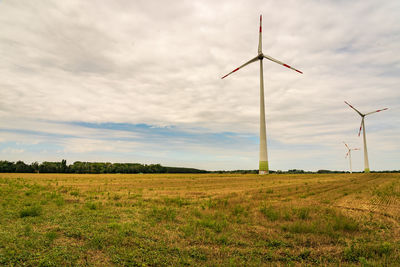 Wind turbines on field against sky