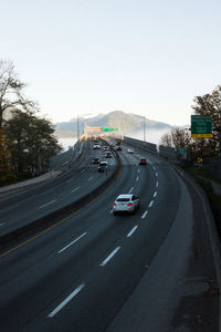 Vehicles on road against sky in city
