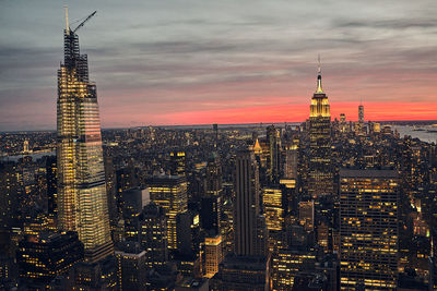 Illuminated buildings in city against sky during sunset