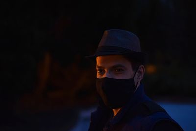 Man wearing mask and hat looking away while standing outdoors