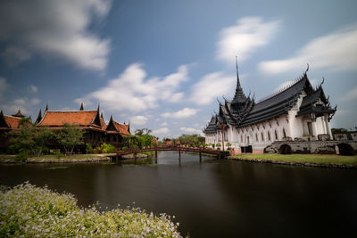 Bridge over river by buildings against sky