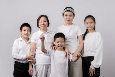 Portrait of happy friends standing against gray background