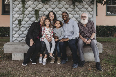 Full length portrait of happy friends sitting outdoors