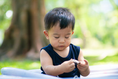 Boy looking at camera while using smart phone outdoors