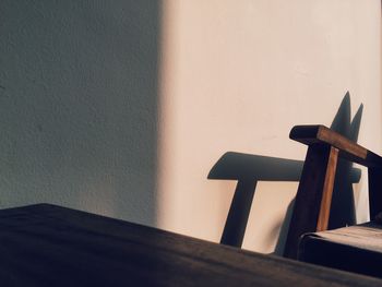 Close-up of wooden table against wall