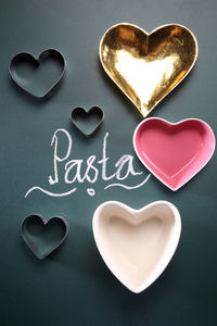 Close-up of heart shape containers with pasta text on black background
