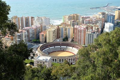 High angle view of modern buildings by sea against sky