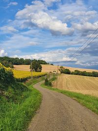 Road amidst agricultural field against sky