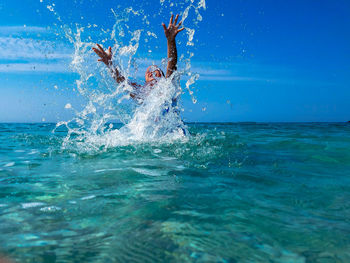 Boy swimming in sea against blue sky