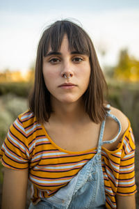 Caucasian young woman with nose piercing looking serious at camera