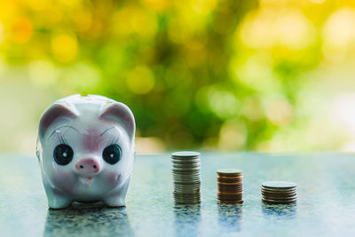 Close-up of coins and piggy bank on table