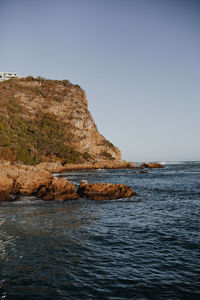 Rock formation on sea against clear sky