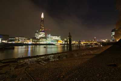 Illuminated buildings by river at night