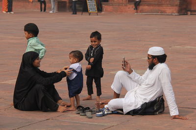 Rear view of two people sitting on floor